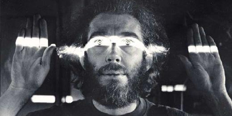 A black and white still, featuring a bearded man